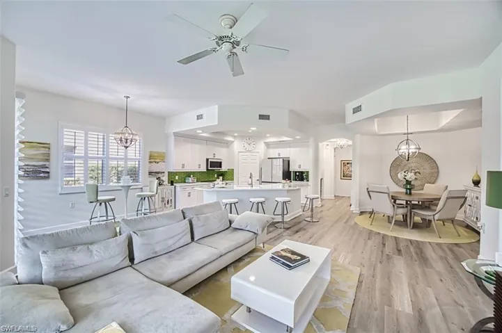Living area with a chandelier, light wood-type flooring, ceiling fan, baseboards, and recessed lighting