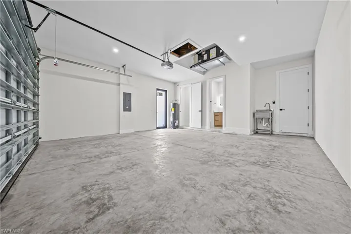Garage with electric panel, water heater, and recessed lighting