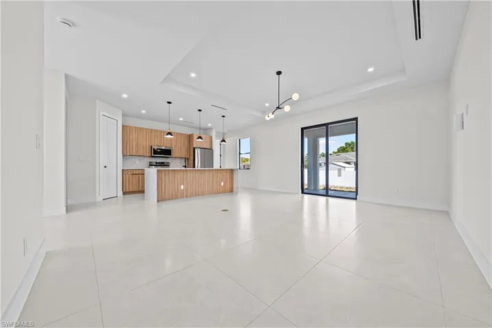 Unfurnished living room featuring a chandelier, a tray ceiling, and light tile patterned flooring