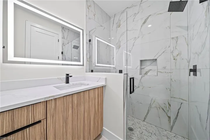 Bathroom with a marble finish shower and vanity