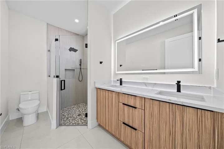 Full bathroom with a stall shower, double vanity, light tile patterned floors, and recessed lighting