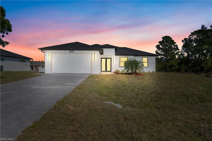 View of front facade with a yard, concrete driveway, stucco siding, and an attached garage