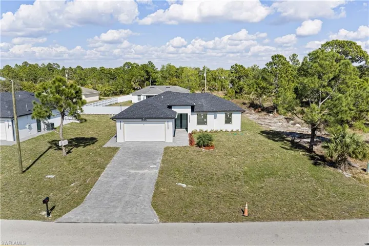 View of front of house featuring decorative driveway, a front lawn, an attached garage, stucco siding, and roof with shingles