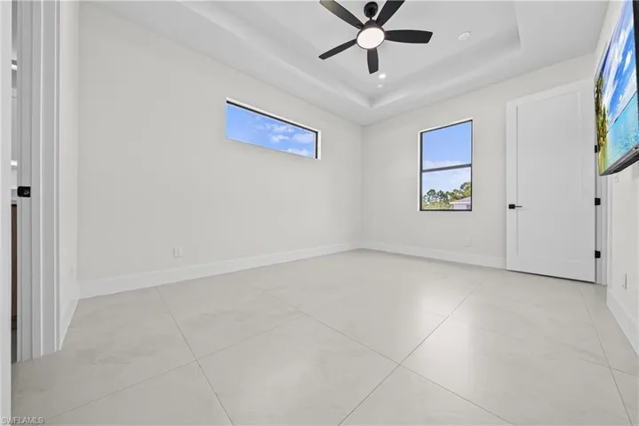 Unfurnished room with a tray ceiling, ceiling fan, recessed lighting, and light tile patterned floors