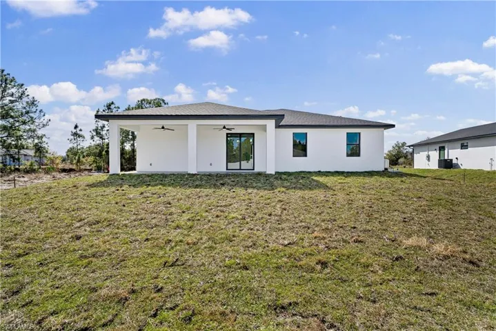 Back of house featuring a ceiling fan, a lawn, and stucco siding