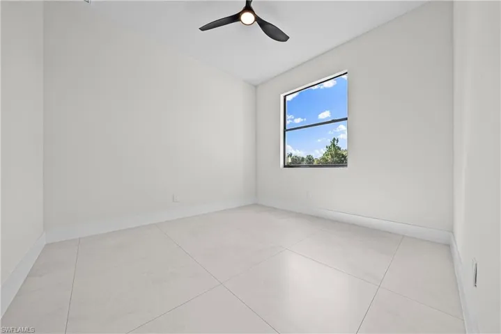 Unfurnished room featuring lofted ceiling, light tile patterned floors, and ceiling fan
