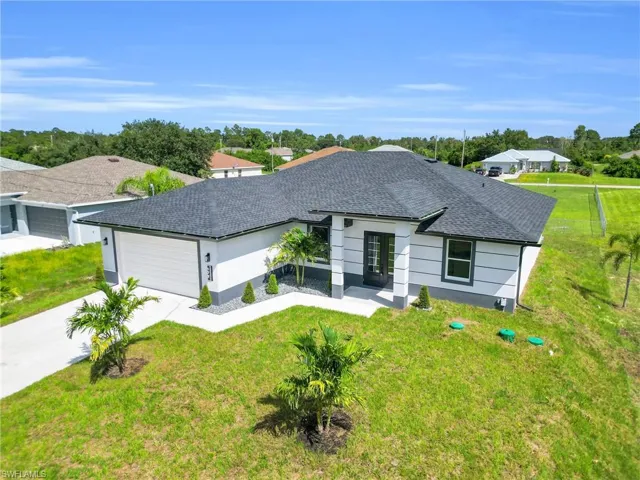 Ranch-style house with a shingled roof, driveway, an attached garage, and a front lawn