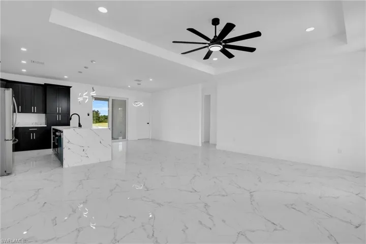 Unfurnished living room featuring a tray ceiling, ceiling fan, and recessed lighting