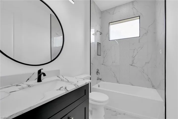 Full bathroom with vanity, a combined bath / shower with marble appearance, and light marble finish floors