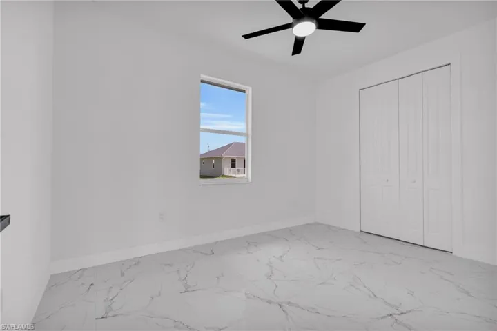 Unfurnished bedroom with light marble finish floors, ceiling fan, and a closet