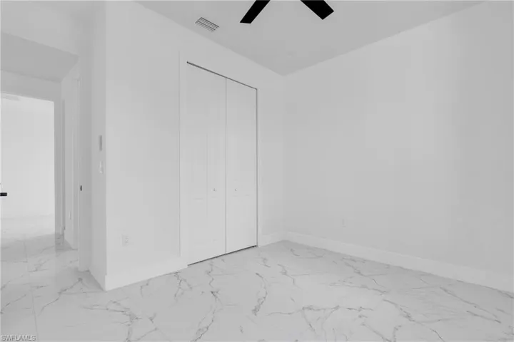 Unfurnished bedroom with light marble finish floors, a closet, and ceiling fan