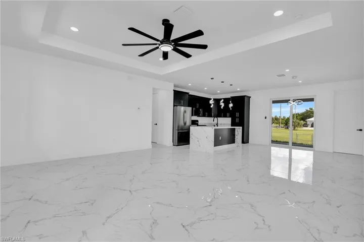 Unfurnished living room with ceiling fan, recessed lighting, and a raised ceiling