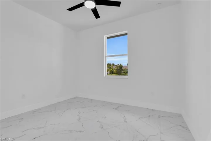 Empty room featuring light marble finish floors and ceiling fan