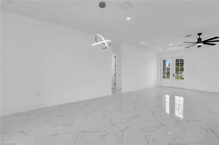 Spare room with french doors, ceiling fan, light marble finish floors, a tray ceiling, and recessed lighting