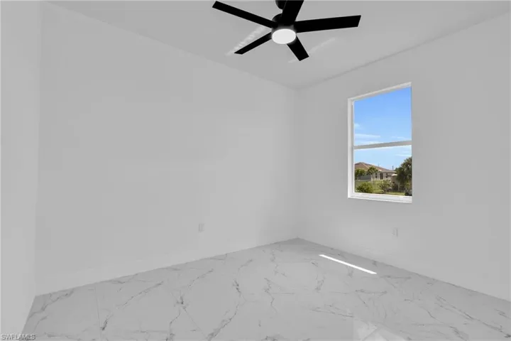 Spare room with light marble finish flooring and ceiling fan