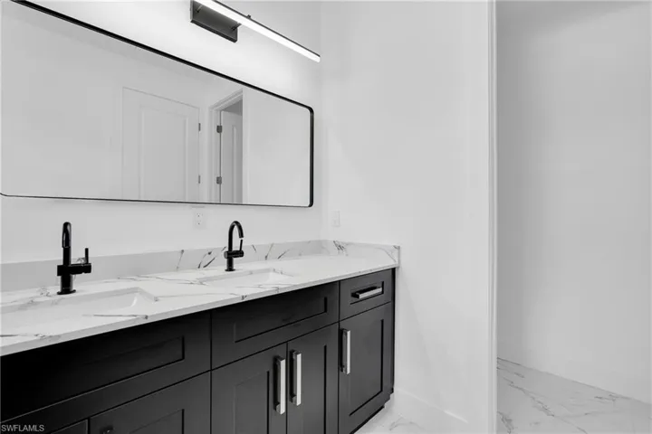 Bathroom featuring double vanity and light marble finish floors