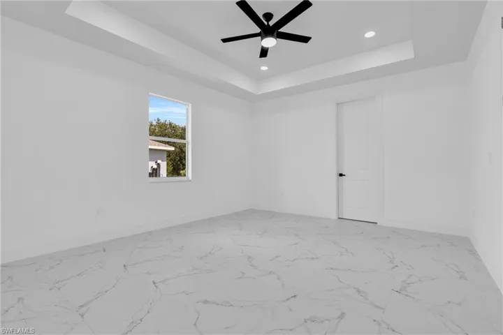 Spare room featuring ceiling fan, light marble finish flooring, recessed lighting, and a raised ceiling