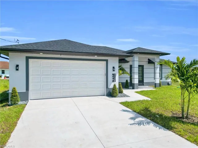 Ranch-style home with a front yard, stucco siding, concrete driveway, and a shingled roof