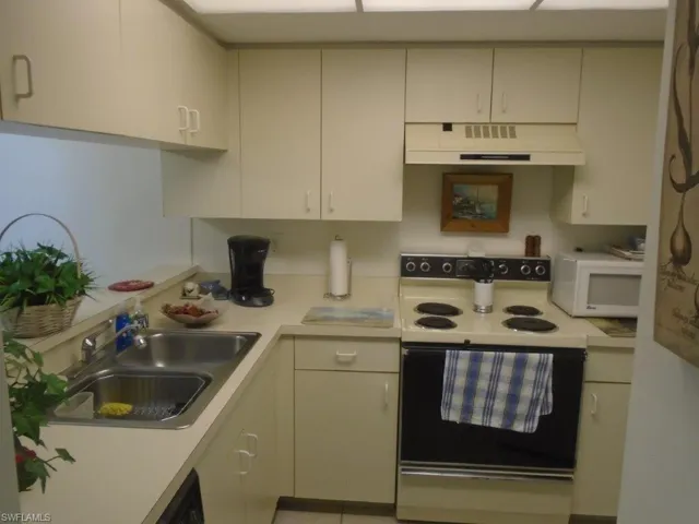 Kitchen featuring sink, white appliances, and premium range hood