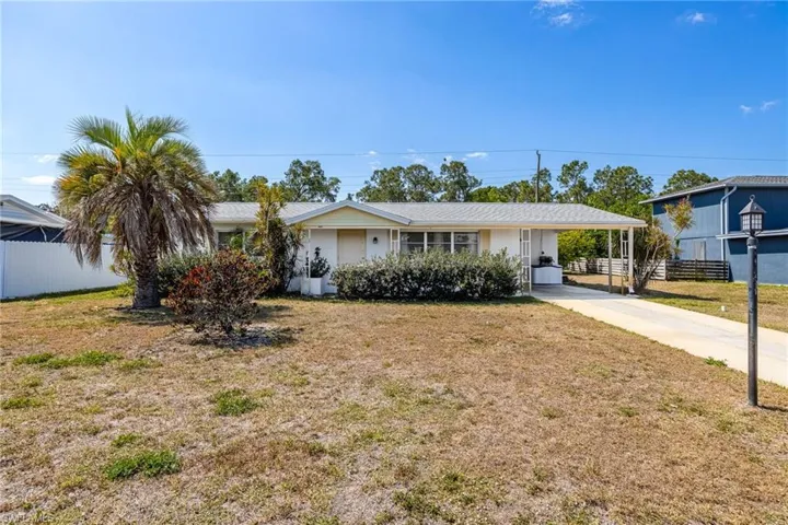 Ranch-style house with fence, a front lawn, a carport, and concrete driveway