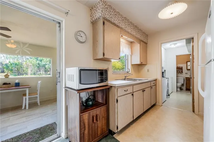 Kitchen with a sink, decorative backsplash, light brown cabinetry, ceiling fan, and light countertops