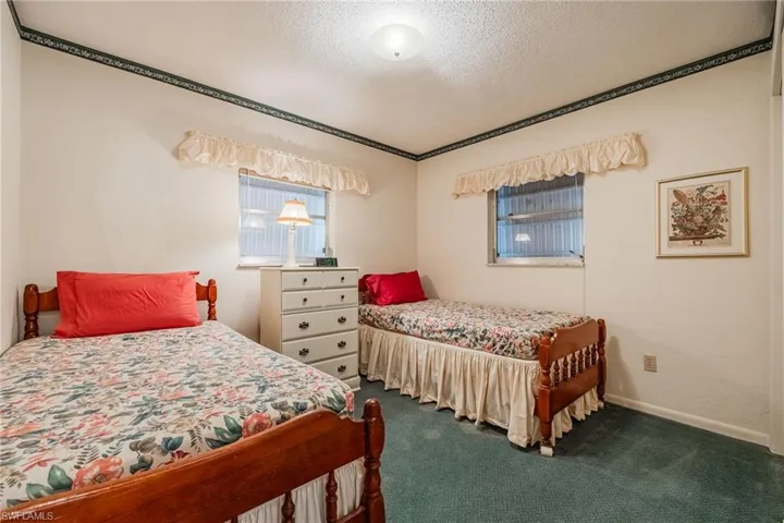 Bedroom featuring dark carpet, baseboards, and a textured ceiling