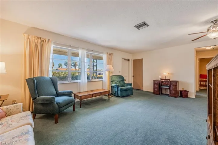 Living area with a ceiling fan, a textured ceiling, visible vents, and carpet