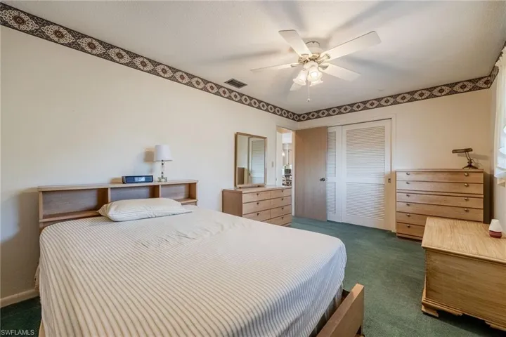Bedroom featuring dark carpet, ceiling fan, visible vents, and a closet