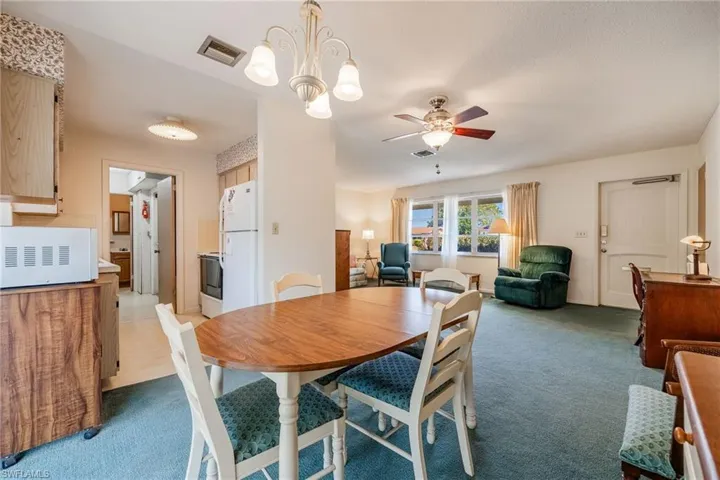 Dining room with light colored carpet, a ceiling fan, and visible vents