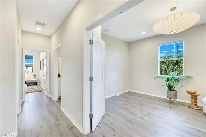 Hallway with light wood-style floors and recessed lighting