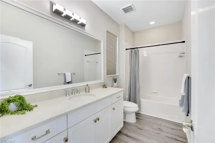 Full bath featuring shower / bath combo with shower curtain, vanity, light wood finished floors, and recessed lighting