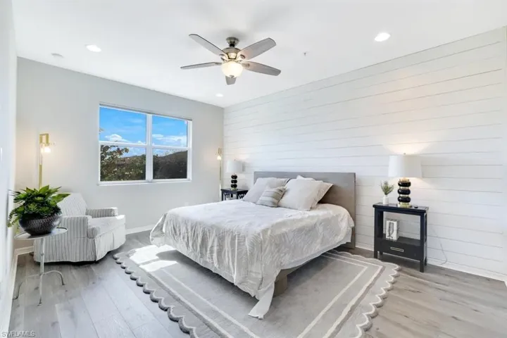 Bedroom with light wood-style floors, ceiling fan, recessed lighting, and wooden walls
