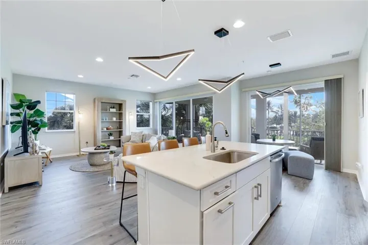 Kitchen featuring white cabinets, decorative light fixtures, a breakfast bar area, light wood-type flooring, and recessed lighting