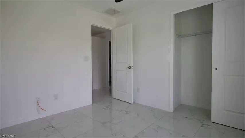 Bright room featuring white walls, large format tile flooring, and a closet with a built-in wire shelf