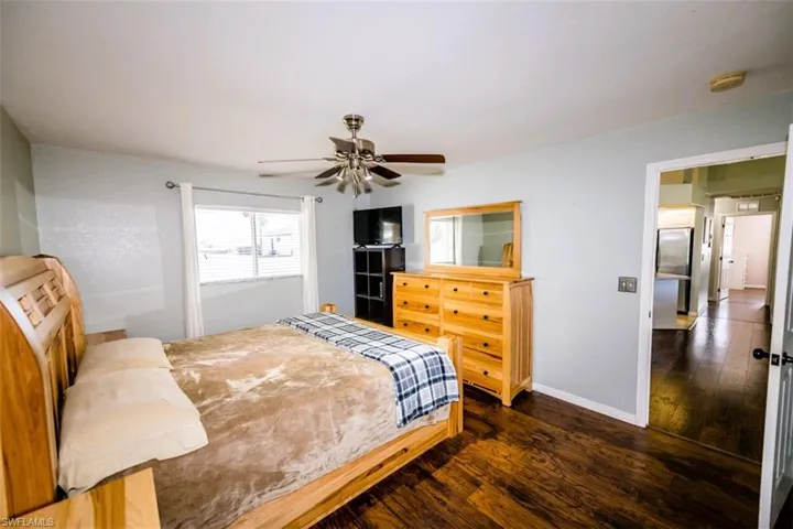 Bedroom featuring dark wood-type flooring, freestanding refrigerator, and a ceiling fan
