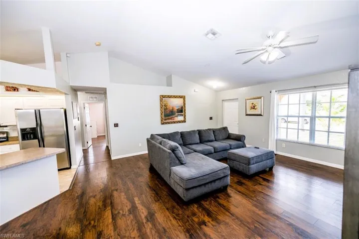 Living room with lofted ceiling, wood finished floors, and ceiling fan