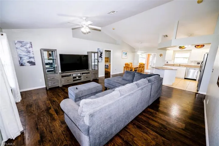 Living area featuring a ceiling fan, vaulted ceiling, and light wood-style flooring