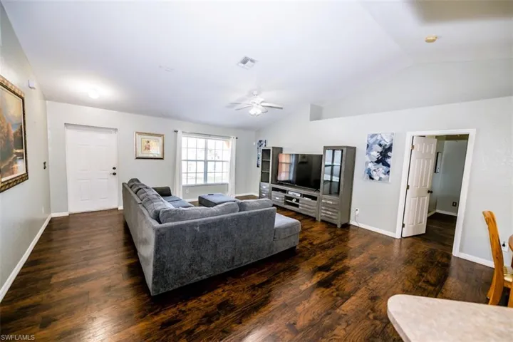 Living area with wood finished floors, vaulted ceiling, and ceiling fan