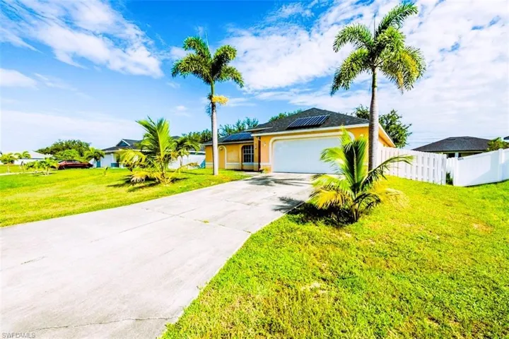 Single story home featuring an attached garage, concrete driveway, roof mounted solar panels, and stucco siding