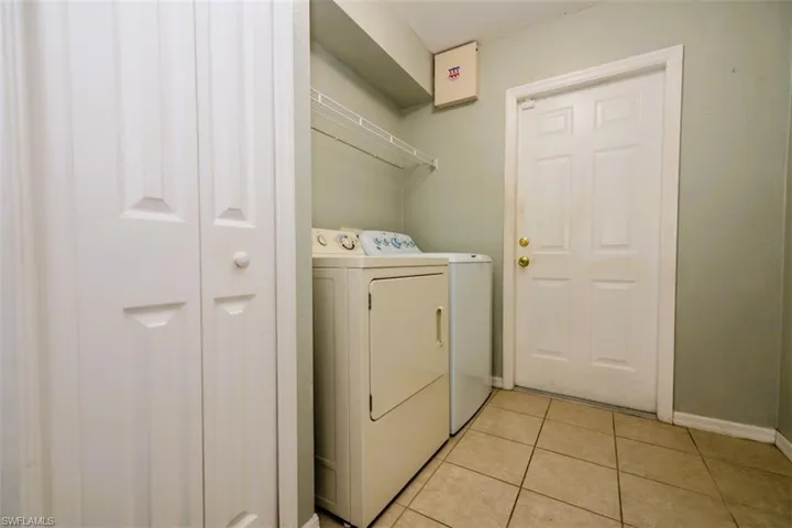 Washroom with independent washer and dryer and light tile patterned floors