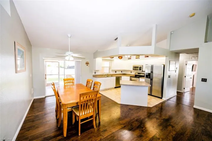Dining area with light wood-style floors, a ceiling fan, and high vaulted ceiling