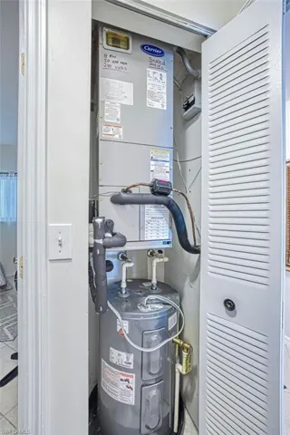 Utility room featuring electric water heater and heating unit