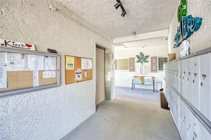 View of property's community featuring a textured wall, mail area, a textured ceiling, and rail lighting