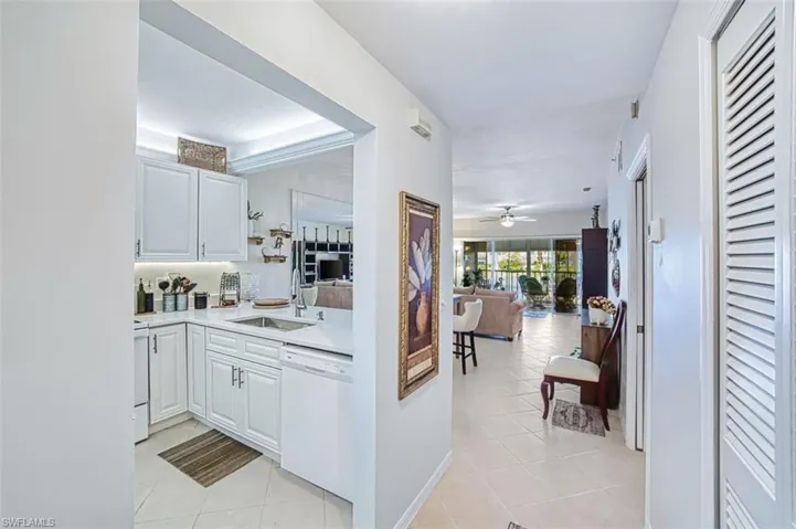 Kitchen with light tile patterned floors, white dishwasher, and white cabinets