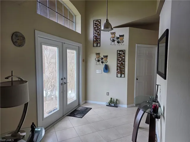 Entrance foyer featuring french doors, light tile floors, and a towering ceiling