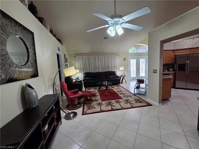 Living room with light tile flooring, a ceiling fan, lofted ceiling