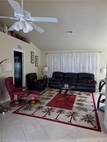 Living area with light tile floors, vaulted ceiling, and a ceiling fan