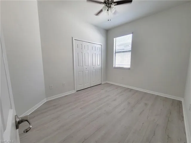 Unfurnished bedroom with light wood finished floors, a closet, and a ceiling fan