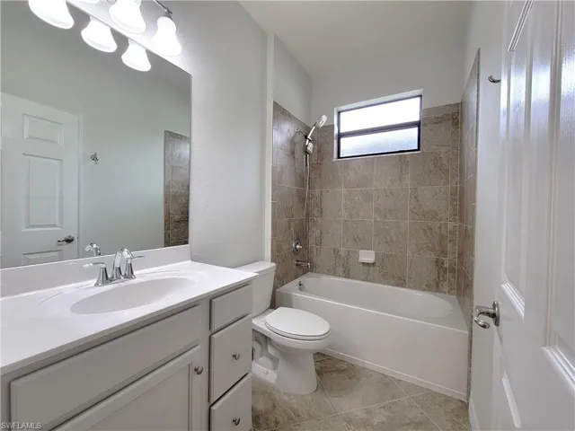 Full bathroom with shower / washtub combination, vanity, and light tile patterned flooring