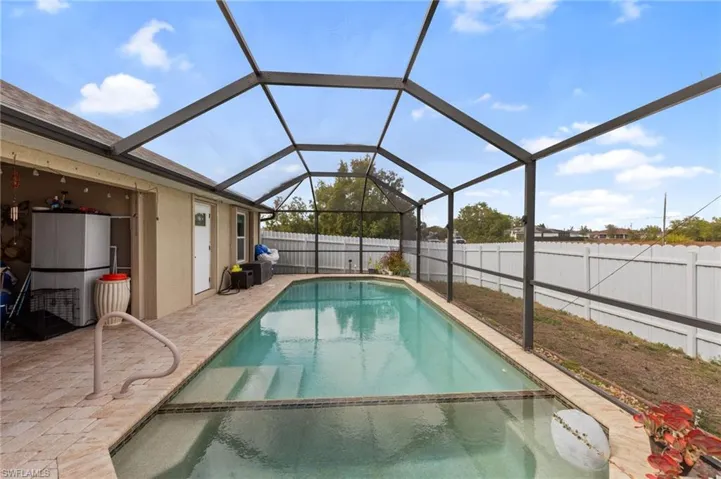 Integrated pool / hot tub featuring a lanai, a sunroom, a fenced backyard, and a patio area